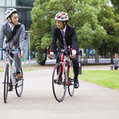 two men in business suits riding bicycles