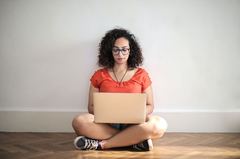 young woman sitting on floor looking at laptop