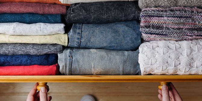 hands pulling open drawer of folded clothes